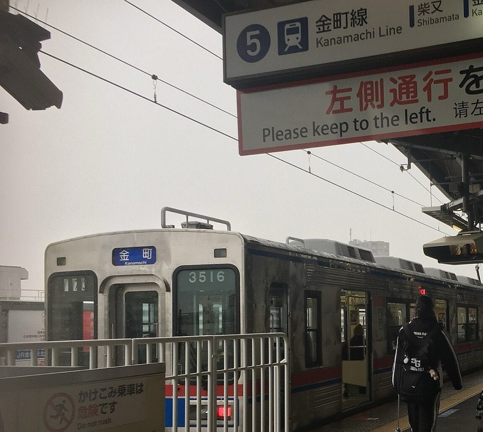 京成高砂 5 号站台,站牌写着「5 金町線 Kanamachi Line, Shibamata」,列车显示「金町 Kanamachi」